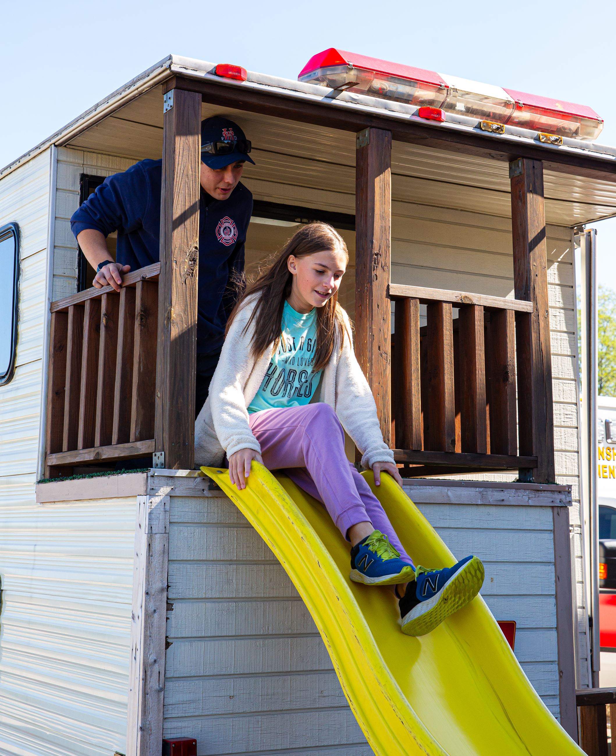 Girl sliding down slide in the Fire Department Smokehouse Trailer